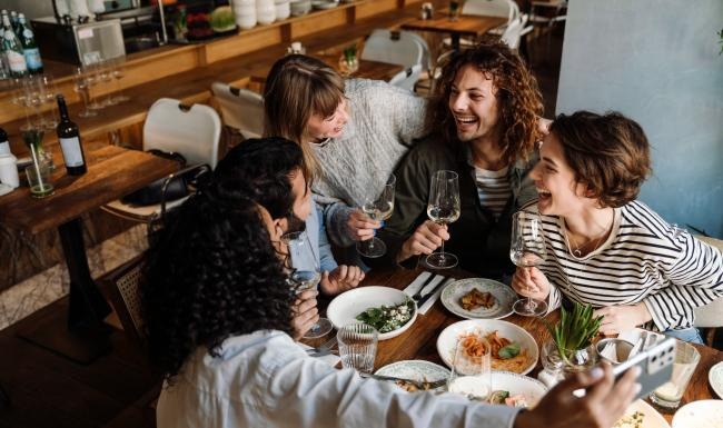 a group of people sitting around a table with food and drinks
